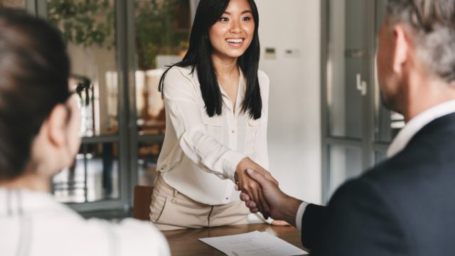 Woman smiling and shaking hands at job interview