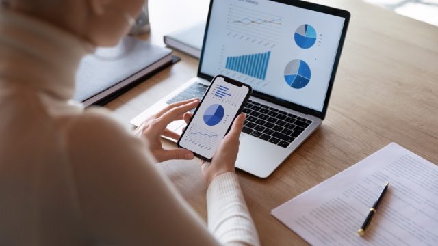 Woman using budgeting app on phone and computer