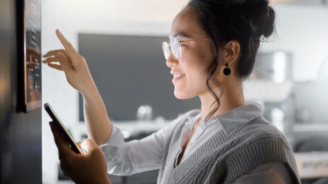 A woman using a tablet to control smart home devices