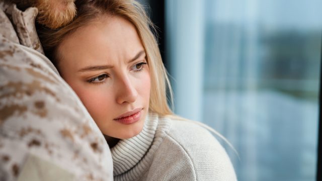 Beautiful romantic couple hugging while standing near window indoors