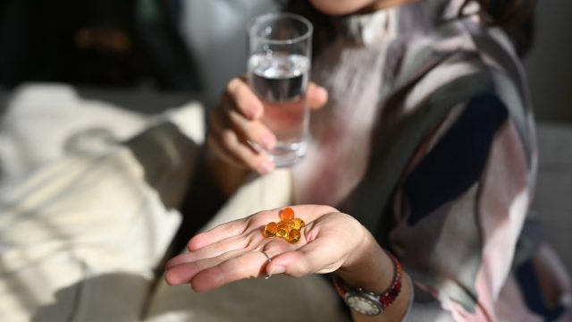 Wellness, Vitamins and Supplements concept, Grey haired senior woman with omega 3 supplement capsule in her hand.