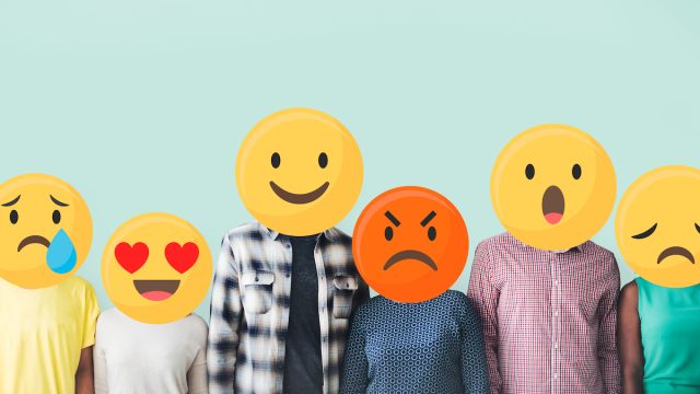 People standing in a row with their faces covered by emojis