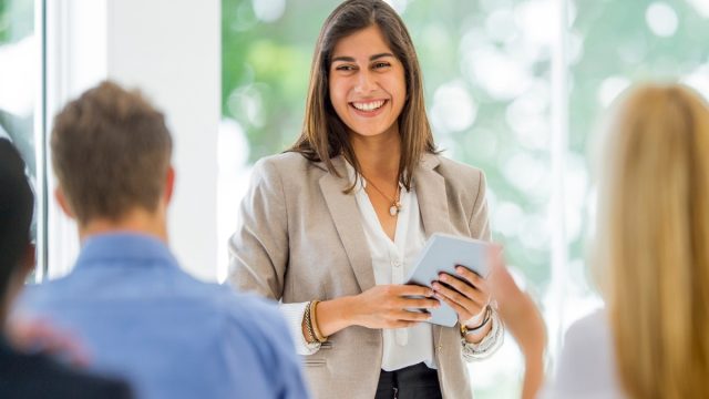 smiling woman speaking in front of peers