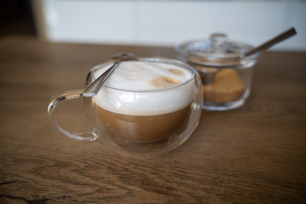 A cup of espresso or latte with brown sugar next to it