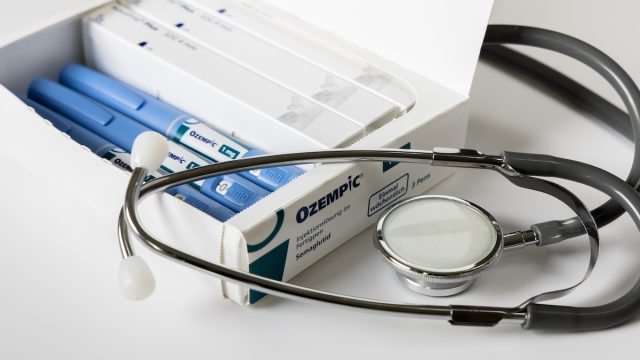 box of ozempic injectable pens alongside a stethoscope on a white background