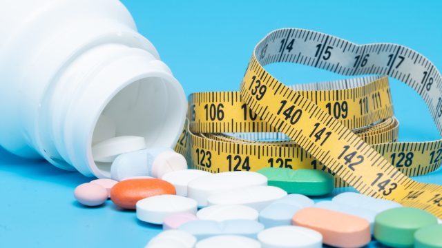 Tape measure and pills on a blue background