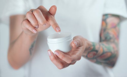 tattooed woman putting her fingers in ointment