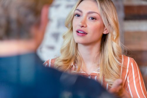 Business man and woman having a conversation. They are both young business people casually dressed. She is talking or listening. Could be an interview or consultant working with a client. She is listening and smiling. One person has his back to us.