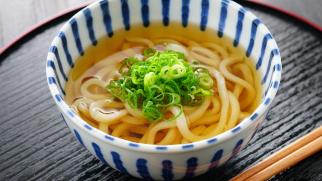 Udon noodle soup with scallions in blue and white bowl