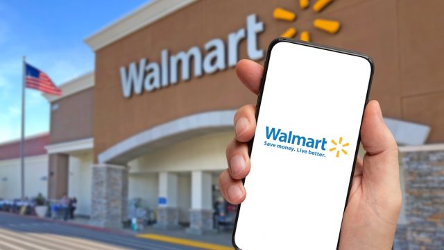 Walmart retailer delivery application on smartphone holding by hand with blurry Walmart store in the background