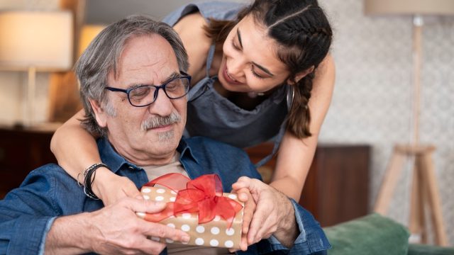A woman giving a senior man a wrapped present