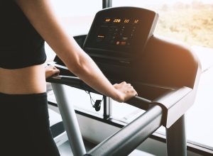 Woman wearing black workout clothes on a treadmill looking at stats on the screen