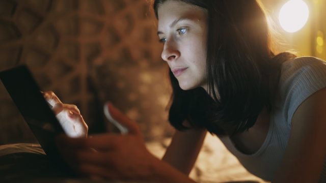 woman using her tablet in bed at night