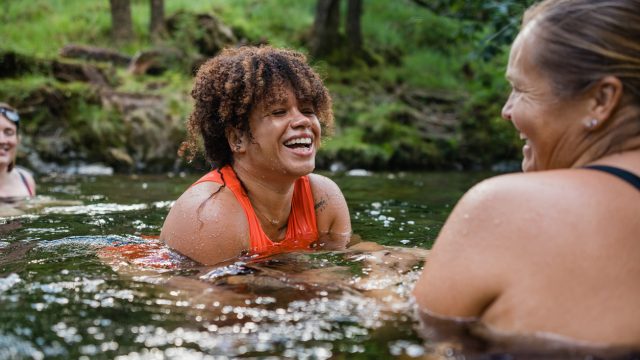Women swimming in a river with friends