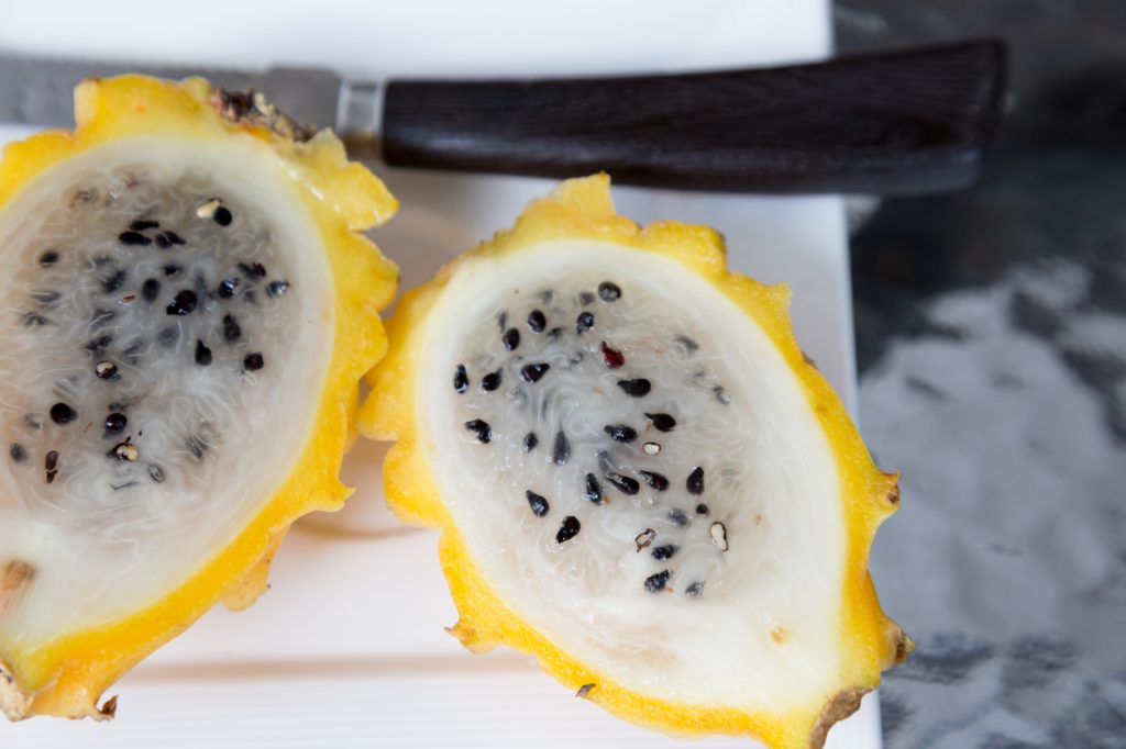 A sliced yellow dragon fruit on a cutting board