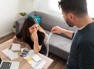 Sad young woman crying with her husband while doing their taxes because of their financial and money problems
