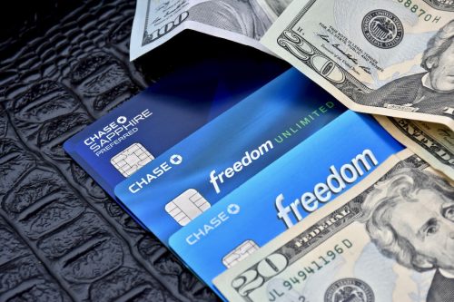 Three blue Chase credit cards and $20 bills on a black surface