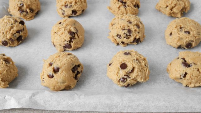 chocolate chip cookie dough balls on a baking sheet with parchment paper