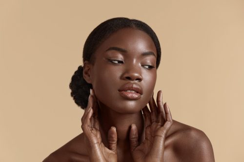 Beauty face. Smiling black woman touching healthy skin portrait. Beautiful girl with glowing skin and natural makeup`. Skin care concept