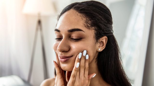 woman touching her cheeks doing face yoga