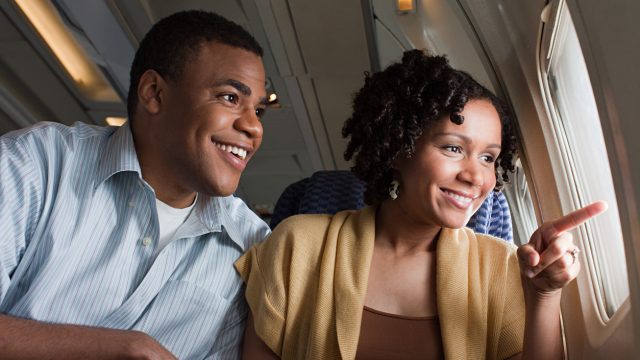 Man and woman on a plane pointing out the window