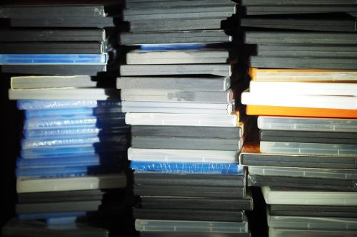 Three piles of old DVDs and Bluerays with dust.