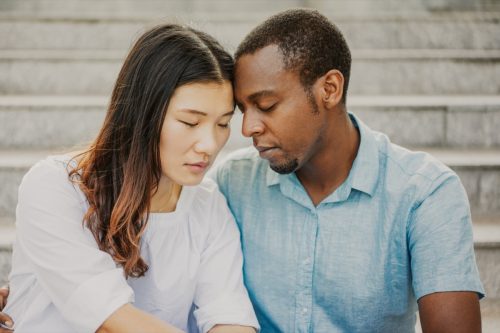 Portrait of sad couple sitting together on stairs.