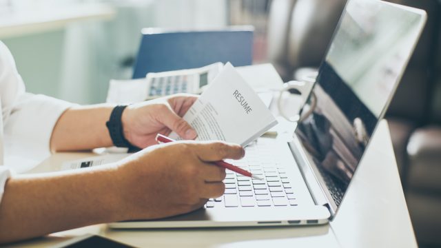 A close up of a person reviewing their resume on printed pages