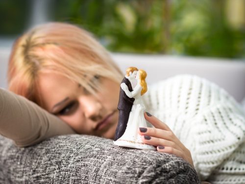woman holding traditional wedding cake topper and frowning