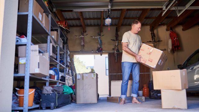 Clearing out some things. Shot of a man carrying a box in a garage.