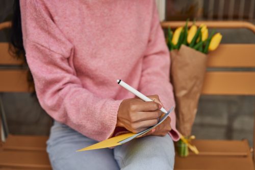 woman writing love letter with yellow tulips.