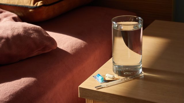 medicine, a thermometer and a glass of water on the bedside table in the morning