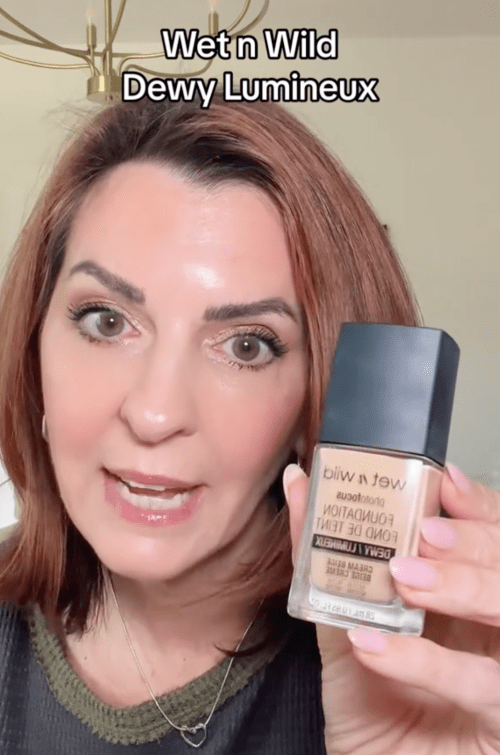 Still from a video of a makeup influencer holding a bottle of foundation