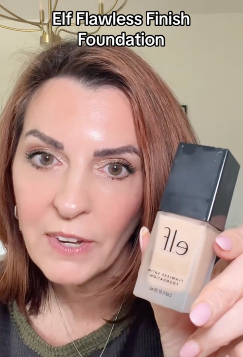 Still from a video of a makeup influencer holding a bottle of foundation