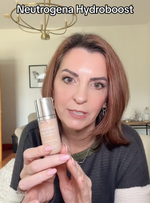 Still from a video of a makeup influencer holding a bottle of foundation