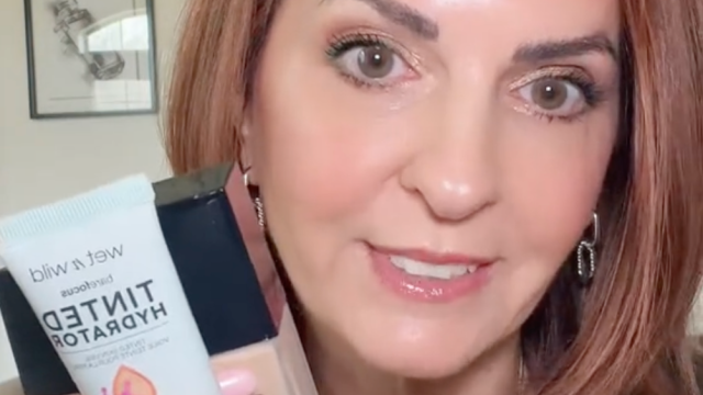 Still from a video of a makeup influencer holding a bottle of foundation