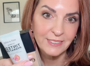 Still from a video of a makeup influencer holding a bottle of foundation