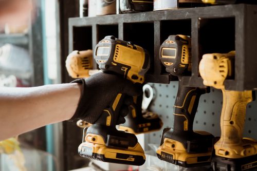 Motorcycle mechanic reaching for electric screwdriver or electric drill or impact tool on the wall to repair Motorcycle or car in garage.motorcycle maintenance and repair concept . selective focus