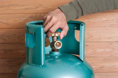 Closeup man's hand operating valve of LPG cylinder for cooking