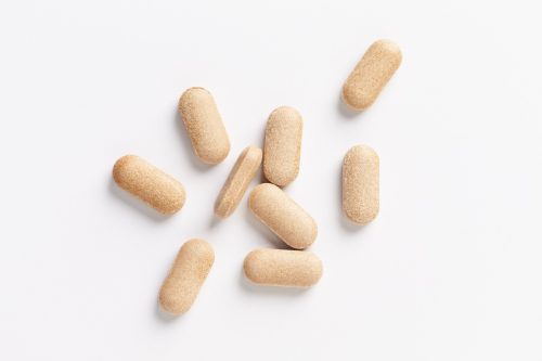 Rhodiola rosea. Golden root, rose root. Herbal pills with healthy medical plant. Healthy supplement on white background. Top view. Copy space.