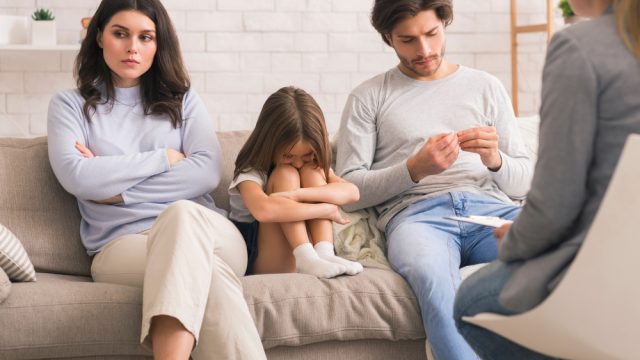 Unhappy child with parents in family therapy