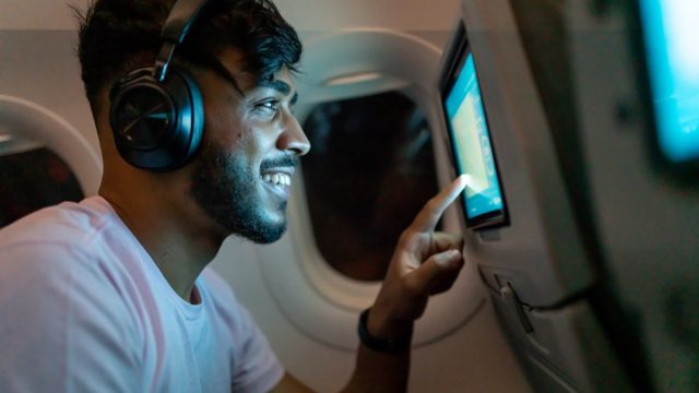 happy passenger using in-flight entertainment system