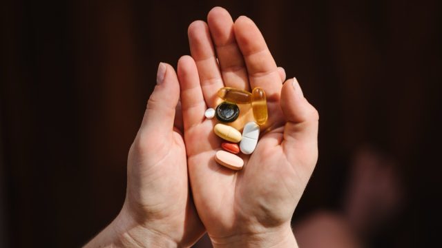 hand holding different multivitamins and supplements