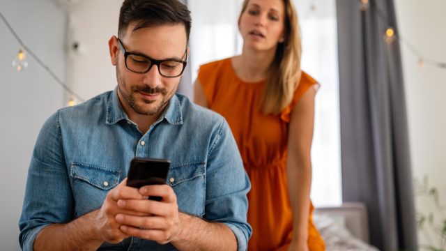 Young couple with jealous woman snooping on texting partner who's cheating