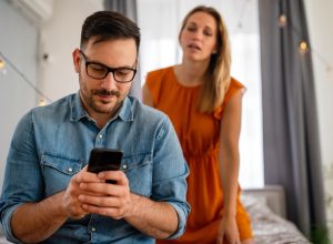 Young couple with jealous woman snooping on texting partner who's cheating