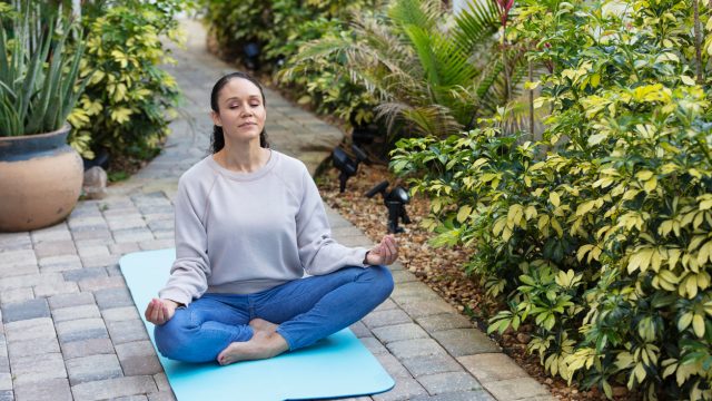 A woman meditating in her backyard