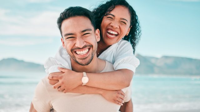 Happy couple smiling and laughing on a beach on vacation