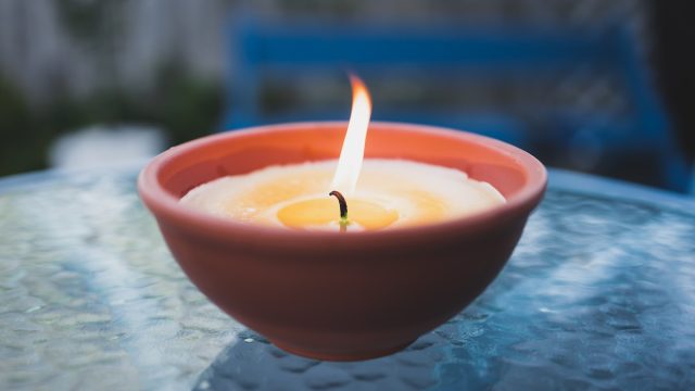 citronella candle with flame outdoor on cafe table setting at dusk