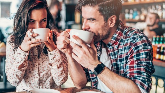 young couple drinking coffee and looking at each other while flirting
