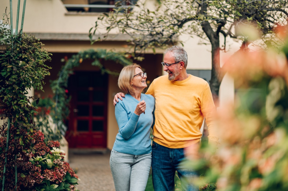 Happy mature couple walking and hugging in front of their house